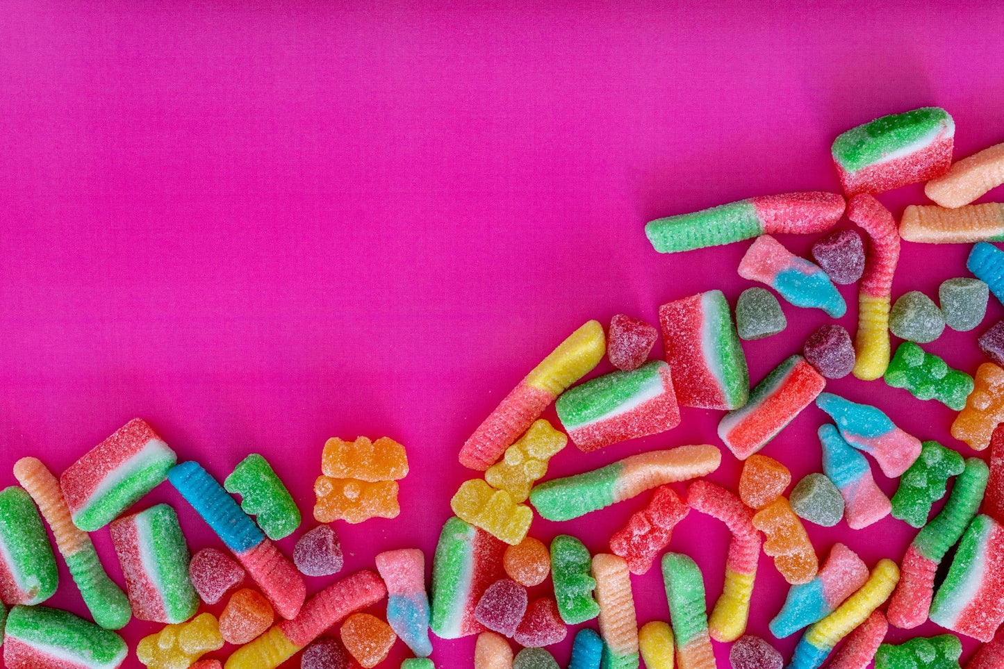 Colorful gummy candies on a pink background